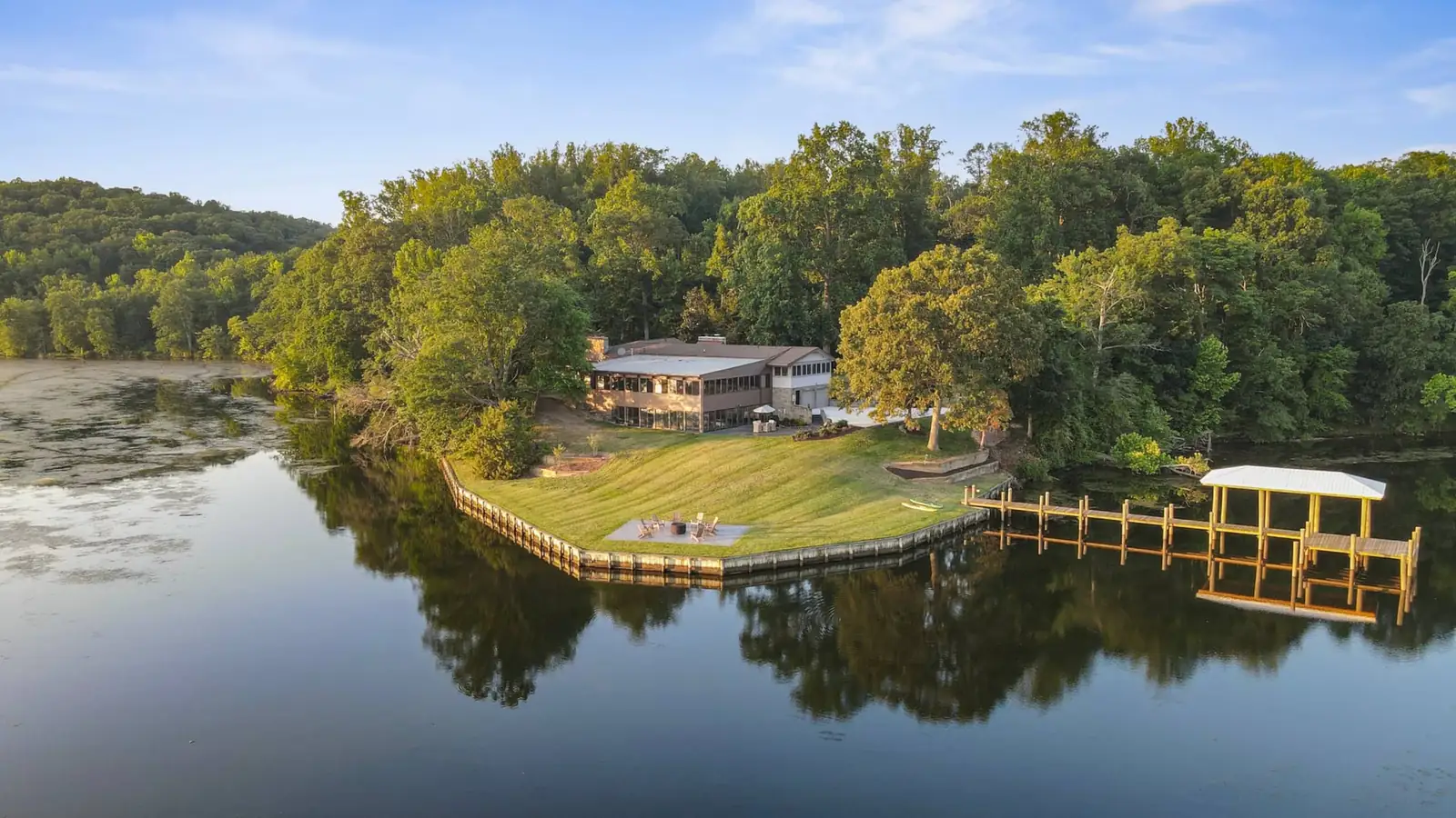 Aerial view of the house among tall trees, the lawn running down to Aquia Creek and the covered pier
