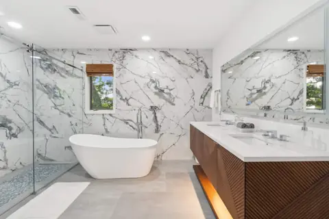 The primary bath with a freestanding soaking tub and marble walls