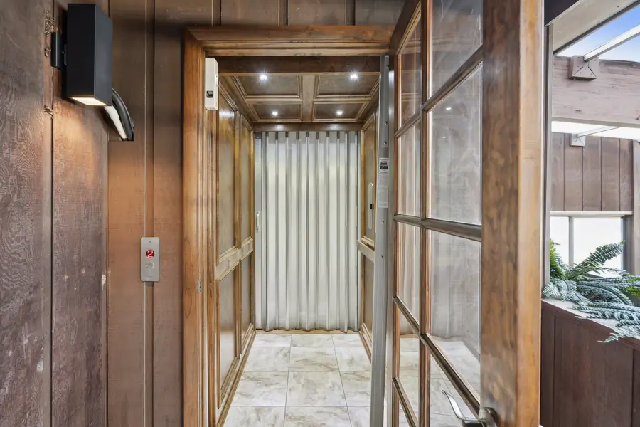 Inside the elevator, with a tiled floor and a lit ceiling