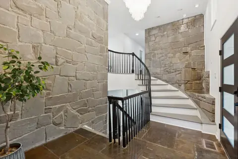 The foyer with a stone wall and a curved staircase