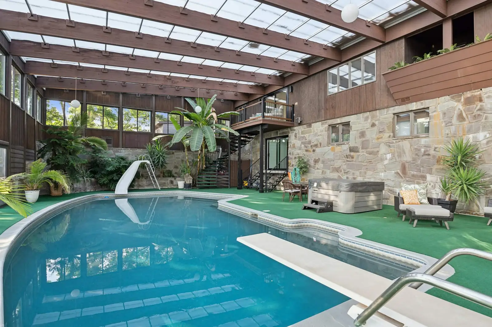 The indoor pool under a timber-framed roof, with the hot tub, a slide and tropical plants