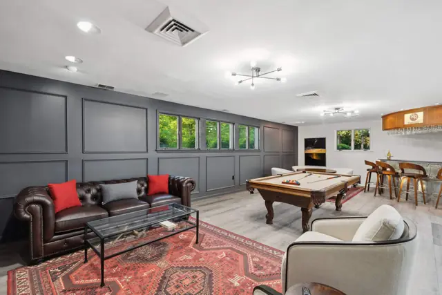 The game room with a billiard table, leather sofa and bar