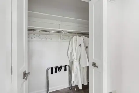 Robes and a luggage rack in a bedroom closet