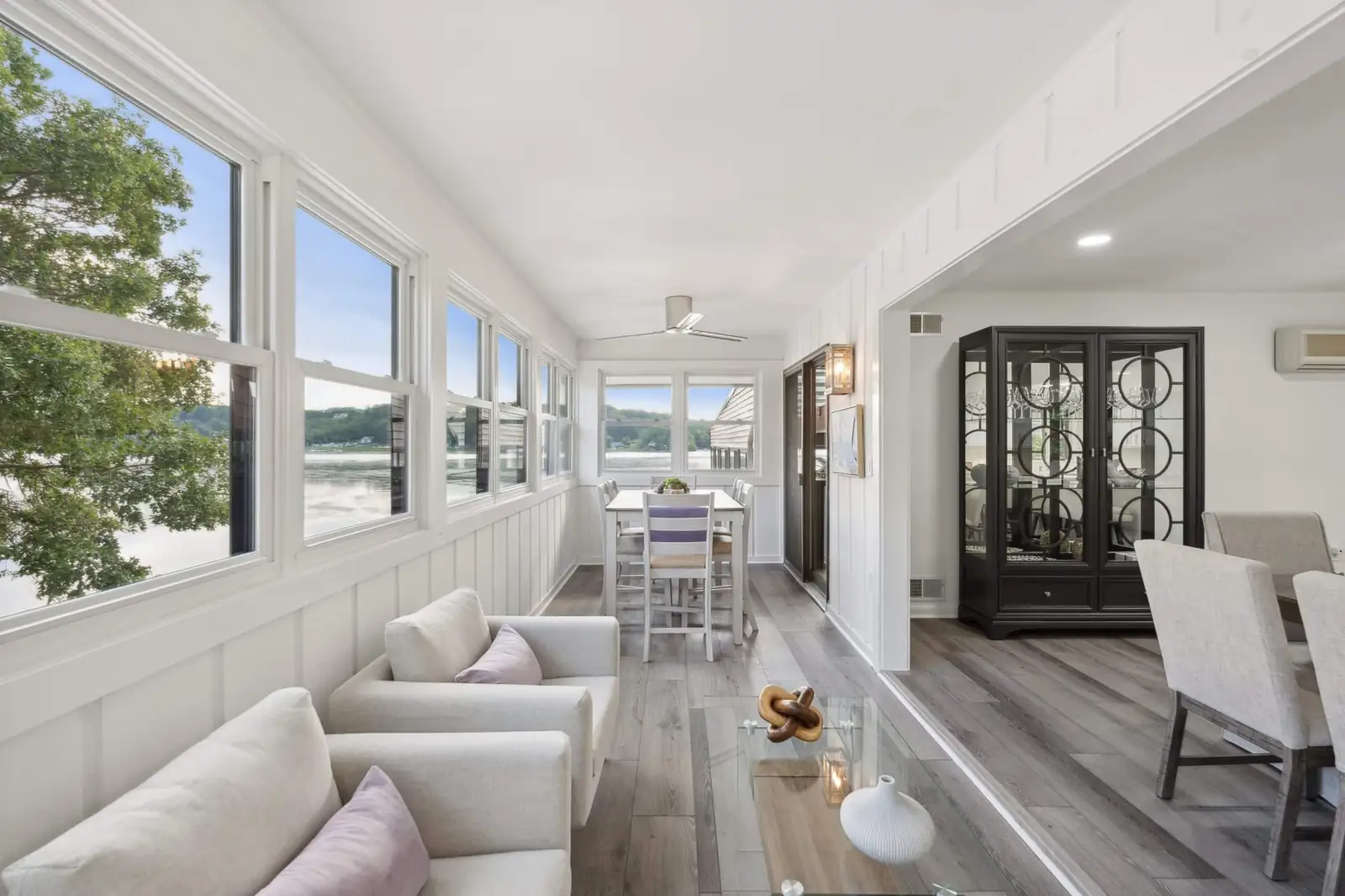 The sunroom with white chairs and windows onto the creek