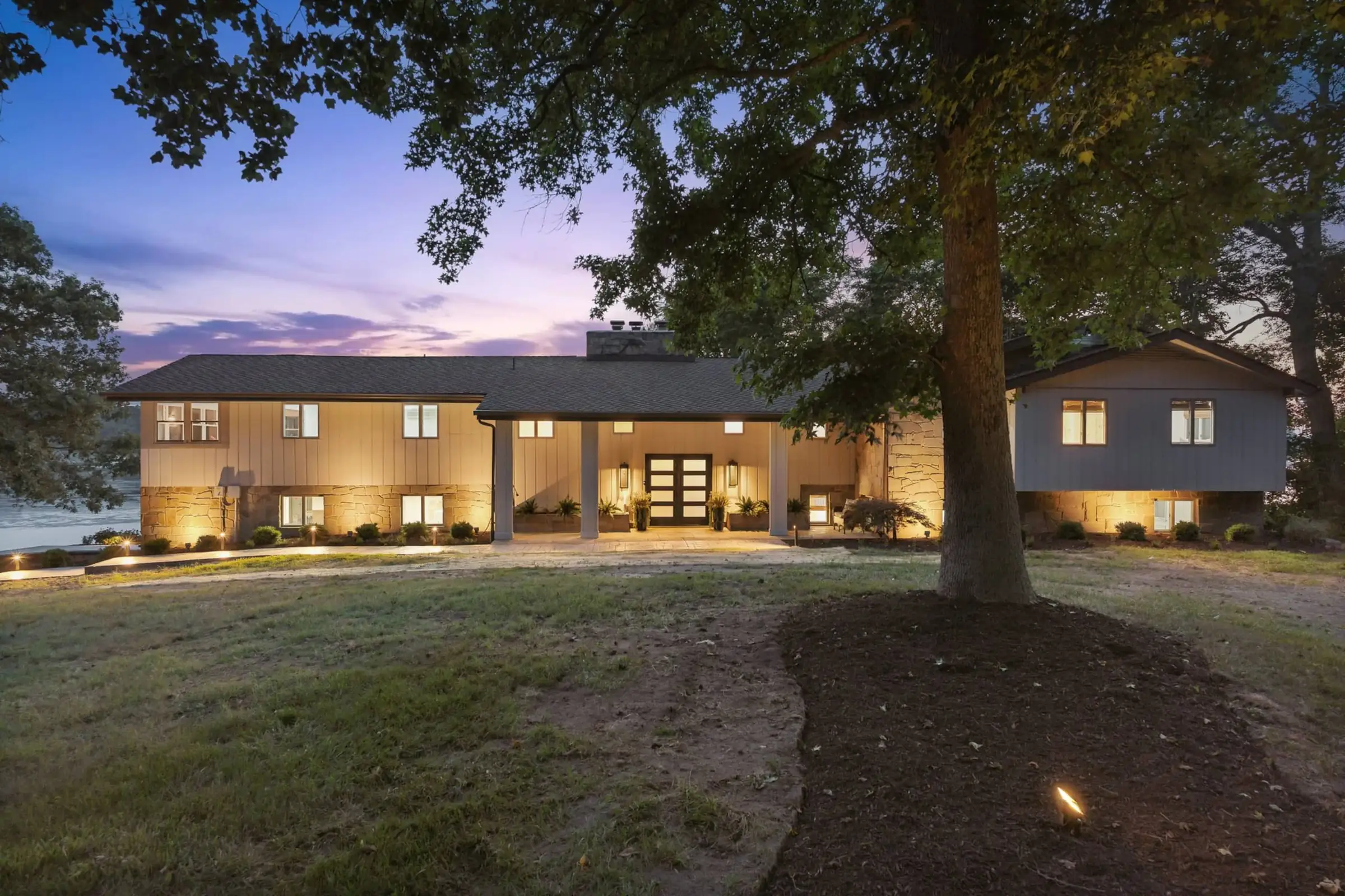 The house at twilight, every window glowing above a wide green lawn